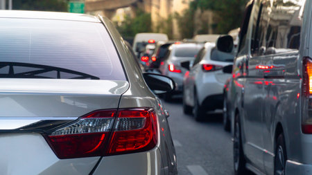 Rear side of luxury grey car driving on the road. Traffic jam on the road with many car at day time. Blurred of many car with town.の写真素材