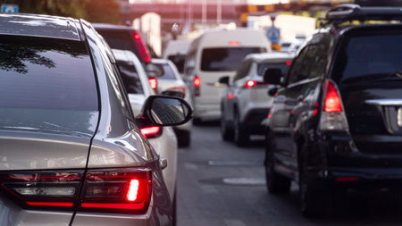 Rear side of luxury bronze car driving on the road. With turn on brake light. Traffic jam on the...