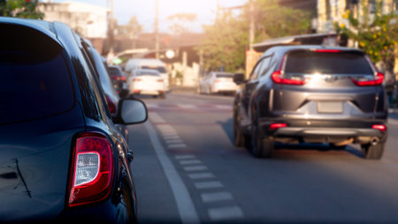 Rear side view luxury of black car. with other cars drive over to the side. Front side of car with sunlight and blurred of trees and town. at day time.の写真素材