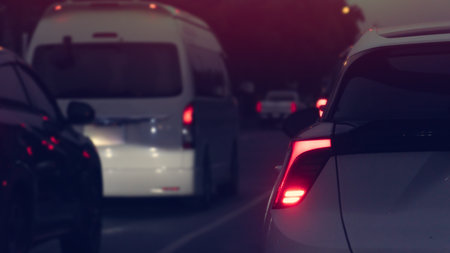 Rear side view of white car with turn on brake light at the night. Traffic on the road with many...