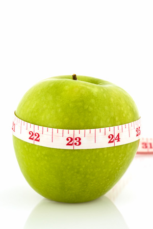green  apple and measuring tape on white backgroundの写真素材