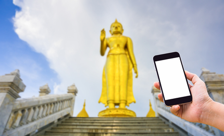 Hand holding smartphone with blank white copy space screen for your put text message in the background of Golden Buddha statue.の写真素材