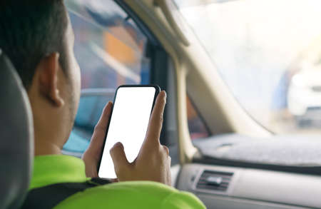 The hand of a man using a smartphone in a car.