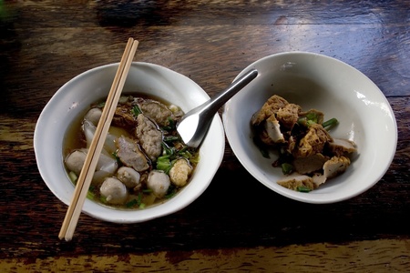China soup with meatball ,vegetable in white bowl ,chopsticks and spoon in the bowl.