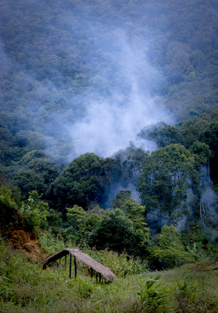 Smoke of Wildfire in Forest  background is Mountain Foreground is hut 