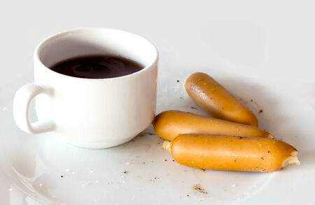 One cup of coffee and three hotdog on white plate.Some pepper and salt spread over on hotdog and plate.の写真素材