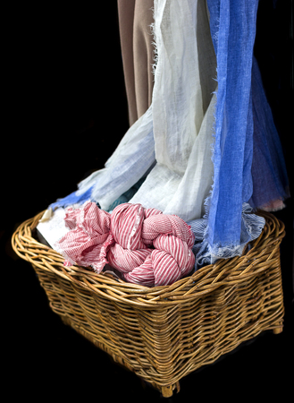 Shawl and scarf from cotton pile in wicker basket.Brown,white and blue shawl hang from top, Edge of a strip of cloth pile in wicker basket.の写真素材