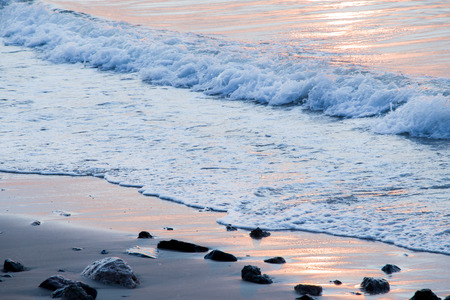 White wave ripple to beach.Rock is shadow.Sunlight reflection on wave and Sea.