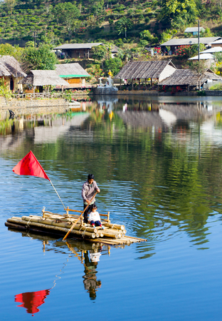 CHIANG MAI, THAILAND - APRIL 16, 2015 : Father push the bamboo raft across river with his daughter in china village at north of Thailand.のeditorial素材