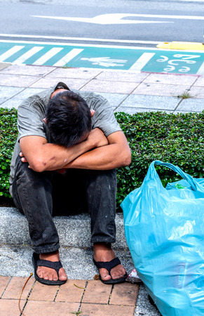 BANGKOK, THAILAND - SEPTEMBER 18, 2015 : Homeless sit on footpath despair in his life, while urban society forsake another.のeditorial素材