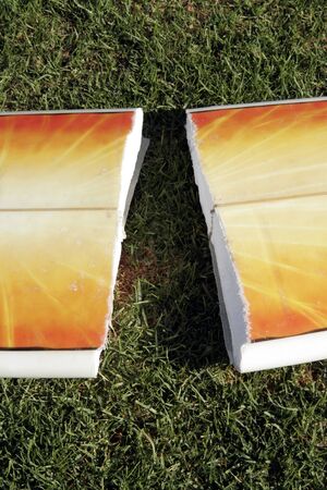 A Broken Yellow, Orange Surfboard On A Green Grass Field, Result Of Dangerous Surfing Conditionsの写真素材