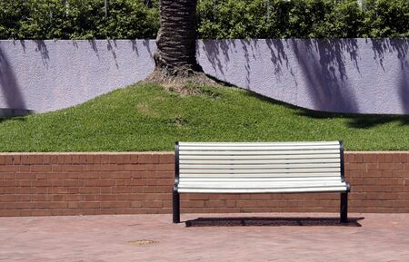 Empty White Bench In Front Of Green Grass And A Purple Wallの写真素材