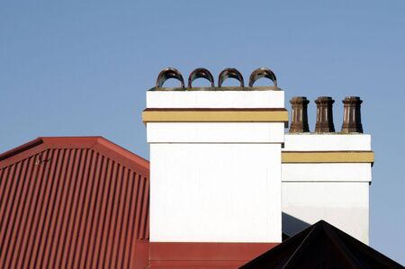 White Chimney On Red Roof In Front Of Clear Blue Skyの写真素材
