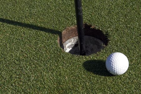 White Small Golf Ball Next To The Hole On The Greenの写真素材