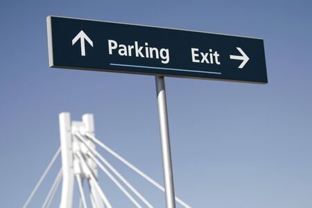 Dark Directions Sign With 'Parking' And 'Exit' Written On It. Clear Blue Sky Backgroundの写真素材