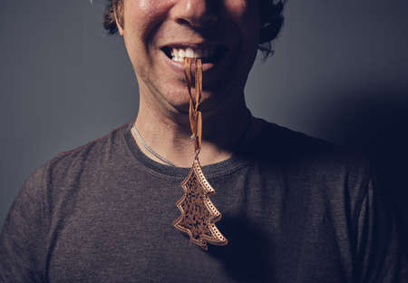 Man holding christmas ornament with mouthの写真素材