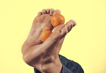 Man holding oranges with his feet