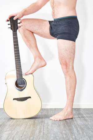 Man in underwear holding acoustic guitarの写真素材