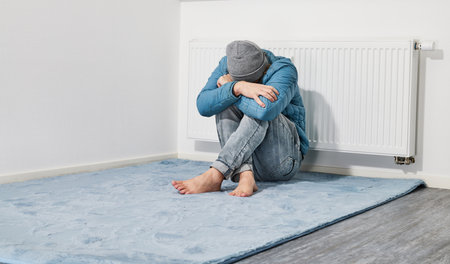 Man freezing in front of heating radiatorの写真素材