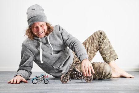 Dad playing with toy motorcycles on the floorの写真素材
