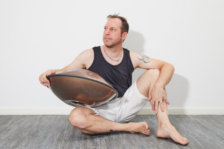 Man sitting on floor playing handpanの写真素材