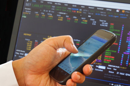 Male trader use smart phone sitting in office.の写真素材