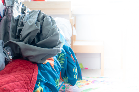 Real messy boy's room showing messy bed with pile of wrinkled bedding. Room for copy and white space...