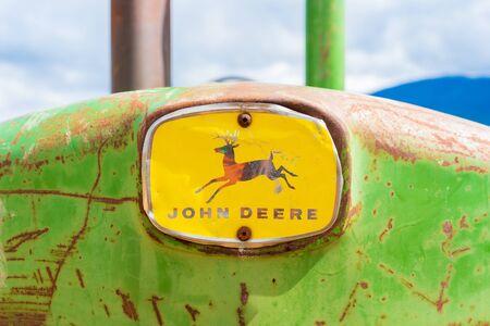 Rusty, old antique John Deere tractor, front nose with the full logo, showing the deer and word mark. Green and yellow classic tractor farm equipment colors.のeditorial素材