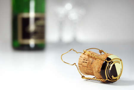 Champagne cork in foreground, bottle and glasses in background, celebrationの写真素材