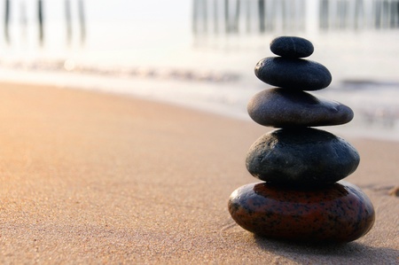 Zen stones balancing on the sandy seashore at sunsetの写真素材