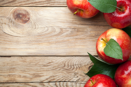 Red apples with green leaves on wooden table. Copy space. Top viewの写真素材
