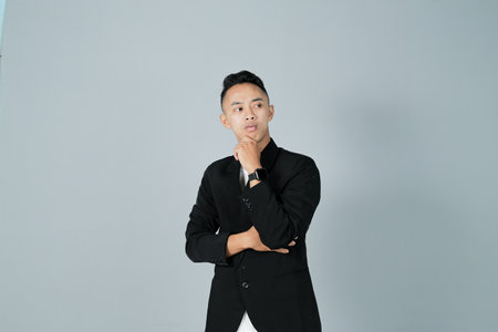 a young man wearing a black shirt is thinking, isolated on a gray backgroundの写真素材
