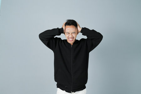 a young man wearing a black shirt is stressed, isolated on a gray backgroundの写真素材