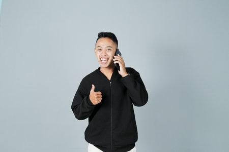 a young man wearing a black shirt is on the phone, isolated on a gray backgroundの写真素材