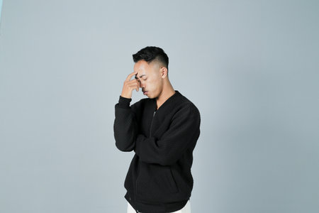 a young man wearing a black shirt is thinking, isolated on a gray backgroundの写真素材