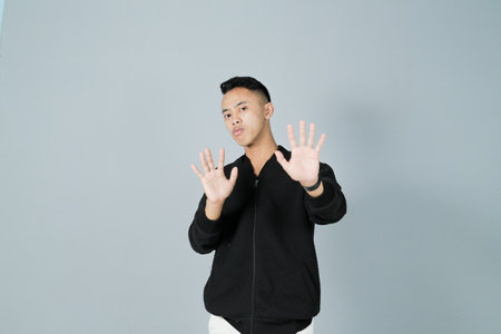 a young man wearing a black shirt showing a rejecting gestureの写真素材