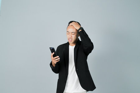 a young man wearing a black suit is stressed, isolated on a gray backgroundの写真素材