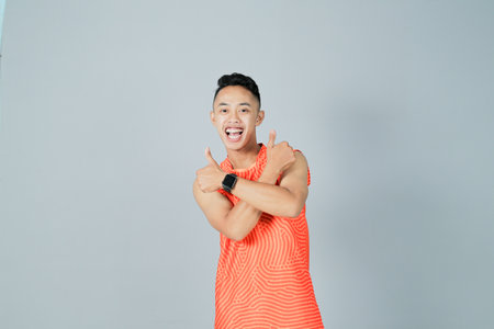 a young man wearing an orange shirt is showing a gesture of enthusiasm, isolated on a gray backgroundの写真素材