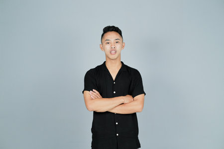 a confident smiling young man wearing a black shirt and folded armsの写真素材