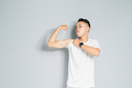 a young man is showing a strong gesture, isolated on a gray backgroundの写真素材