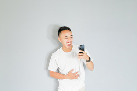 a young Asian man is smiling while on a video callの写真素材