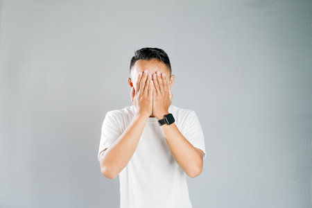 a young asian is covering his face with his handsの写真素材