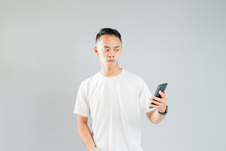 a young Asian is worried while looking at his smartphoneの写真素材