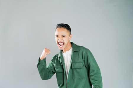 a young asian man with a passionate expression, isolated on a gray backgroundの写真素材