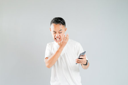 a young Asian is worried while looking at his smartphoneの写真素材