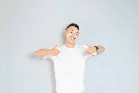 a young asian is giving his two thumbs upの写真素材