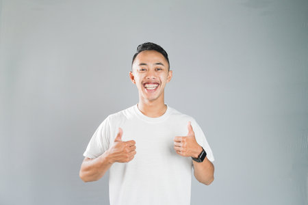 a young asian is giving his two thumbs upの写真素材