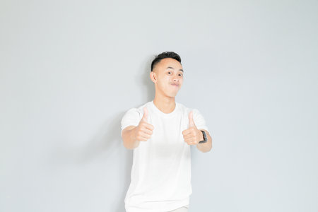 a young asian is giving his two thumbs upの写真素材