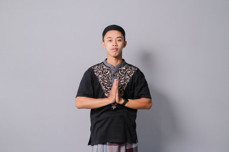 young asian muslim giving greeting, isolated on gray backgroundの写真素材