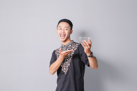 young asian muslim holding bowl, isolated on gray backgroundの写真素材